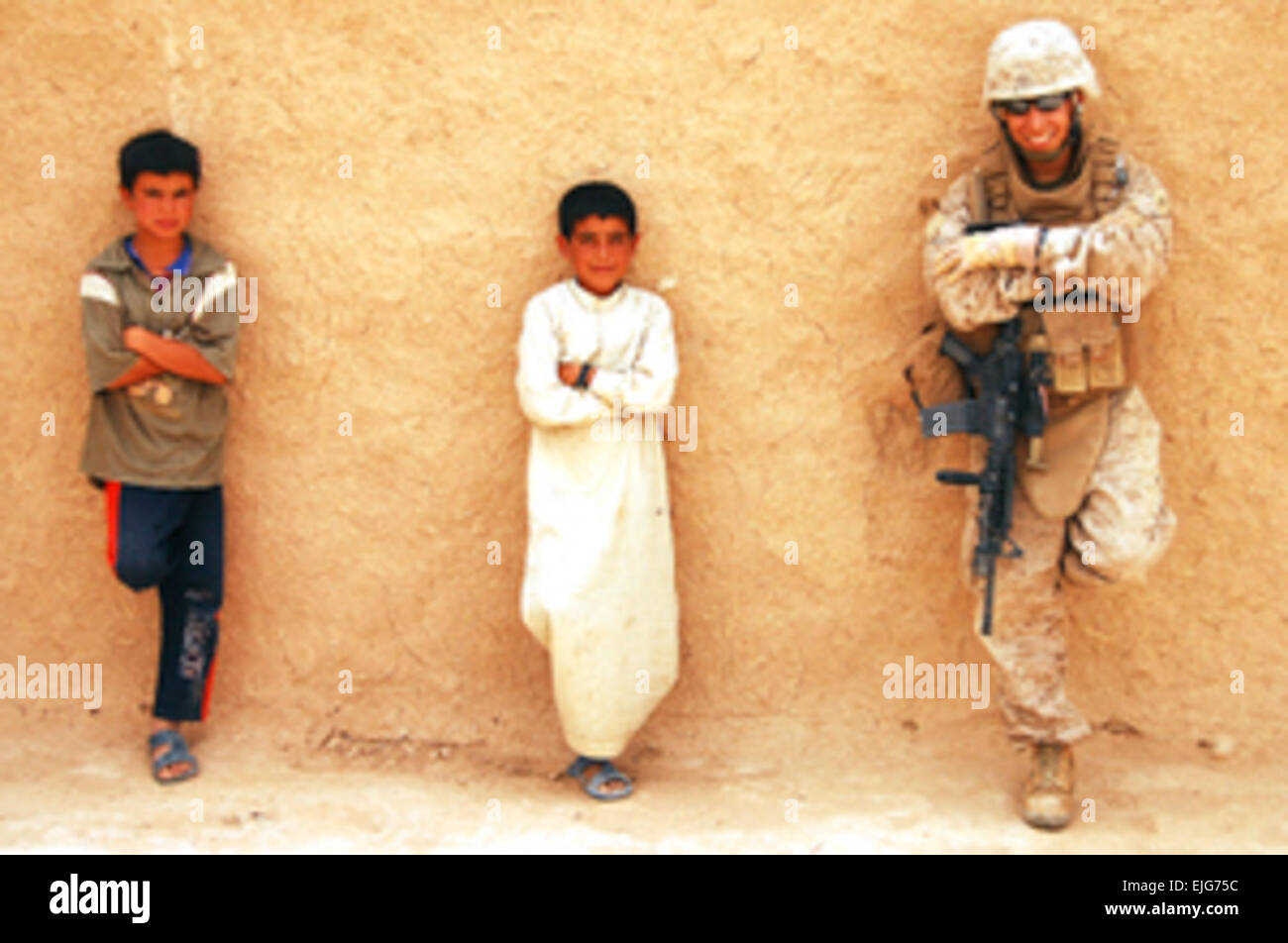 U.S. Marine Corps Cpl. Johathan R. Segovia, personnel security detail, 1st Marine Expeditionary Force, a ground combat element attached to Multi-National Force - West, relaxes with Iraqi children in Sha-ban, Iraq, July 9, 2008.  Cpl. Taylor J. Schulz, U.S. Marine Corps. Released Stock Photo