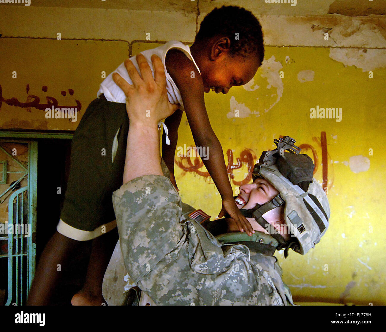 Cpl. David Stigers, from Bravo Company, 2nd Battalion, 6th Infantry Regiment, attached to Task Force 1st Battalion, 35th Armored Regiment, 2nd Brigade Combat Team, 1st Armored Division, plays with a young Iraqi boy while his team questions his mother in order to fill out a census form in Tameem, Iraq, Aug. 7, 2006.  Tech. Sgt. Jeremy T. Lock.      . Stock Photo