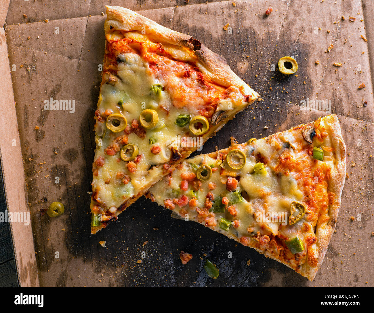 Slices of cold messy leftover pizza in a delivery box. Stock Photo