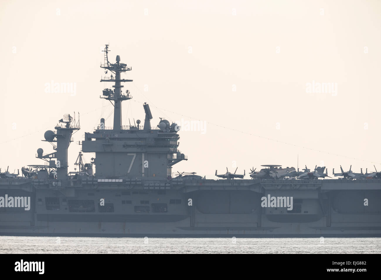 Stokes Bay, Solent, UK. 25th March, 2015. The Nimitz class aircraft carrier USS Theodore Roosevelt at anchor in Stokes Bay in the Solent, 25th March 2015. Credit:  Anthony Hatley/Alamy Live News Stock Photo