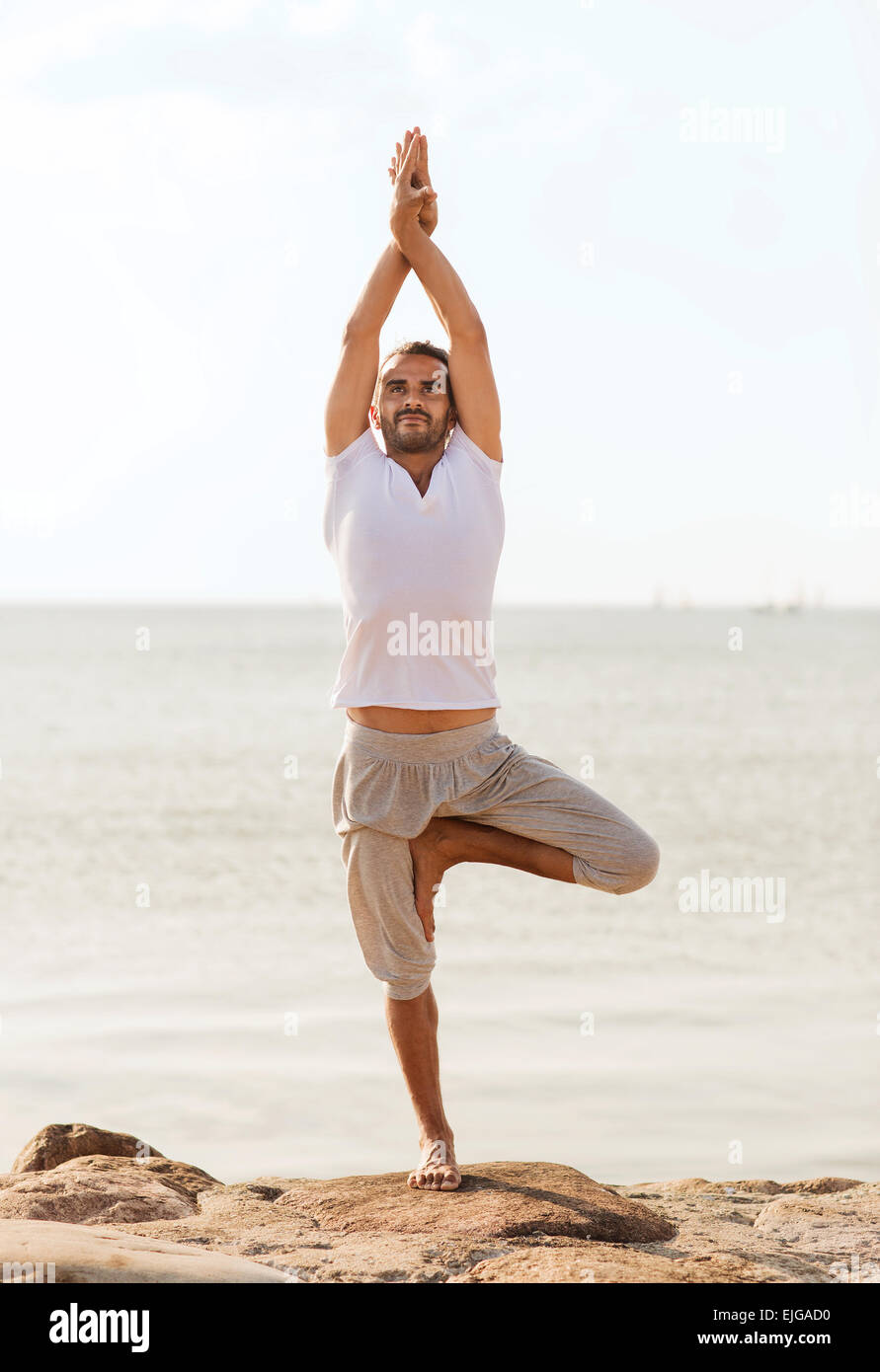 smiling man making yoga exercises outdoors Stock Photo