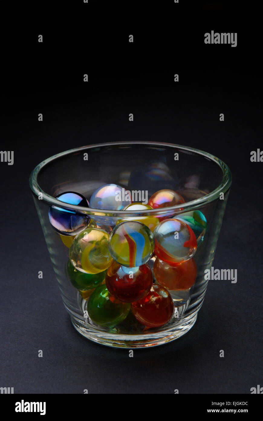 Colored marbles in glass on black background Stock Photo
