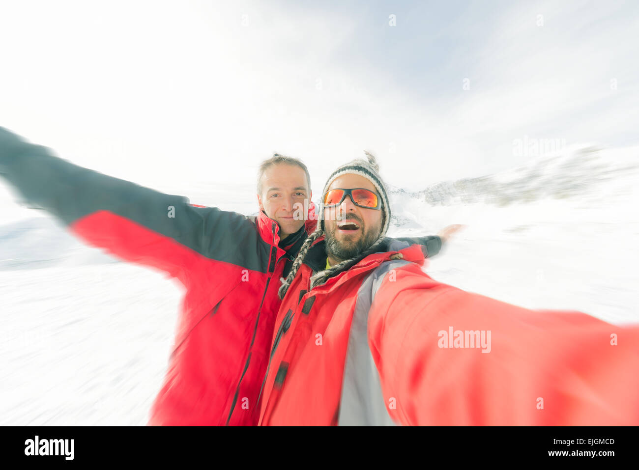 Couple of sport men taking selfie in backlight on the mountains. Concept of friendship and sharing achievements. Stock Photo