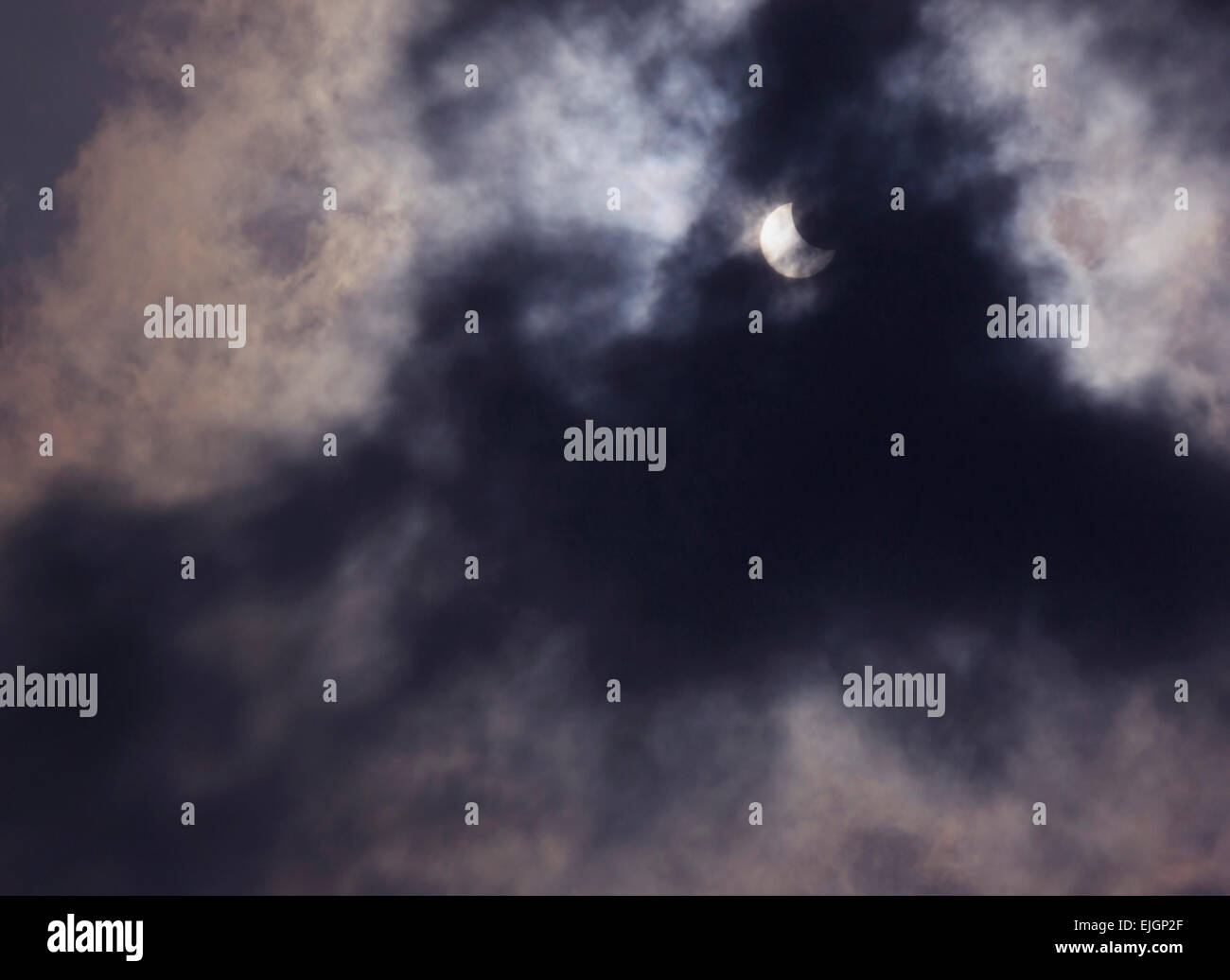 view on partial solar eclipse behind clouds Stock Photo