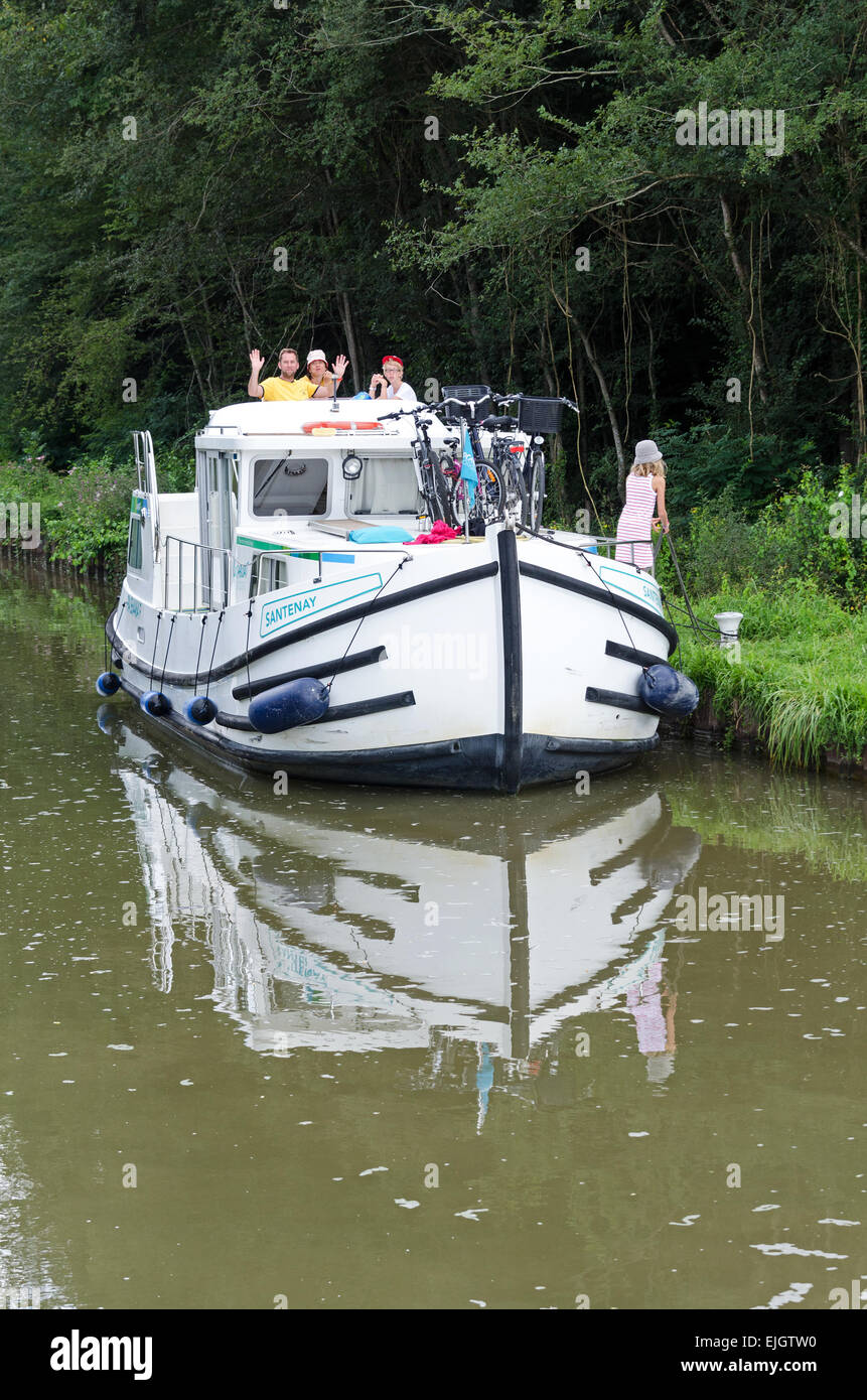 A family has moored their rented canal boat on the bank of the Canal du Centre upriver from Fragnes, France. Stock Photo