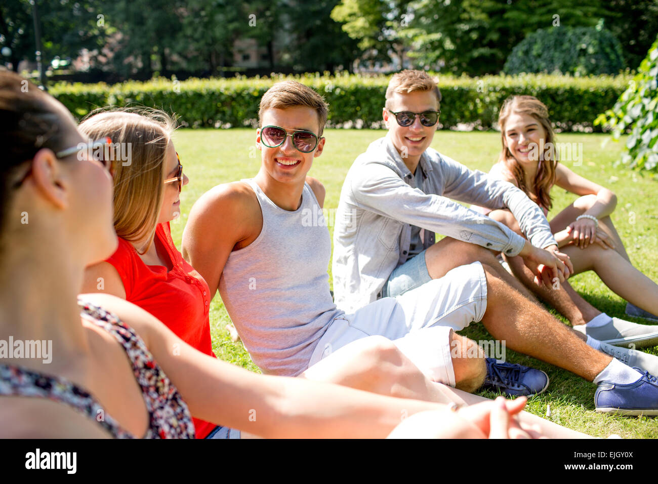 group of smiling friends outdoors sitting in park Stock Photo - Alamy