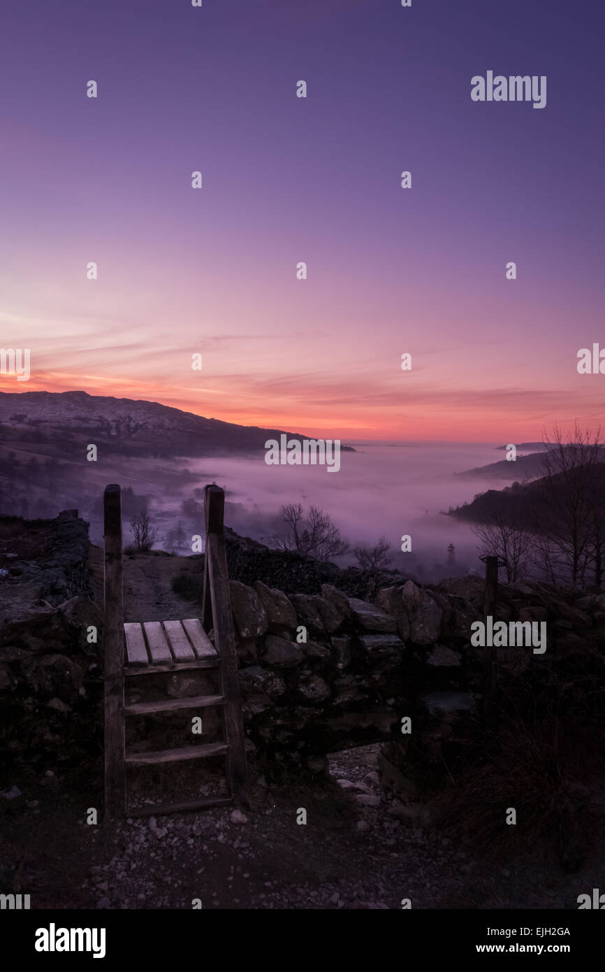 Winter scene: Beautiful pink sunrise scene looking into Ambleside at sunrise from the side of the Fairfield horseshoe, The Lake District, England Stock Photo