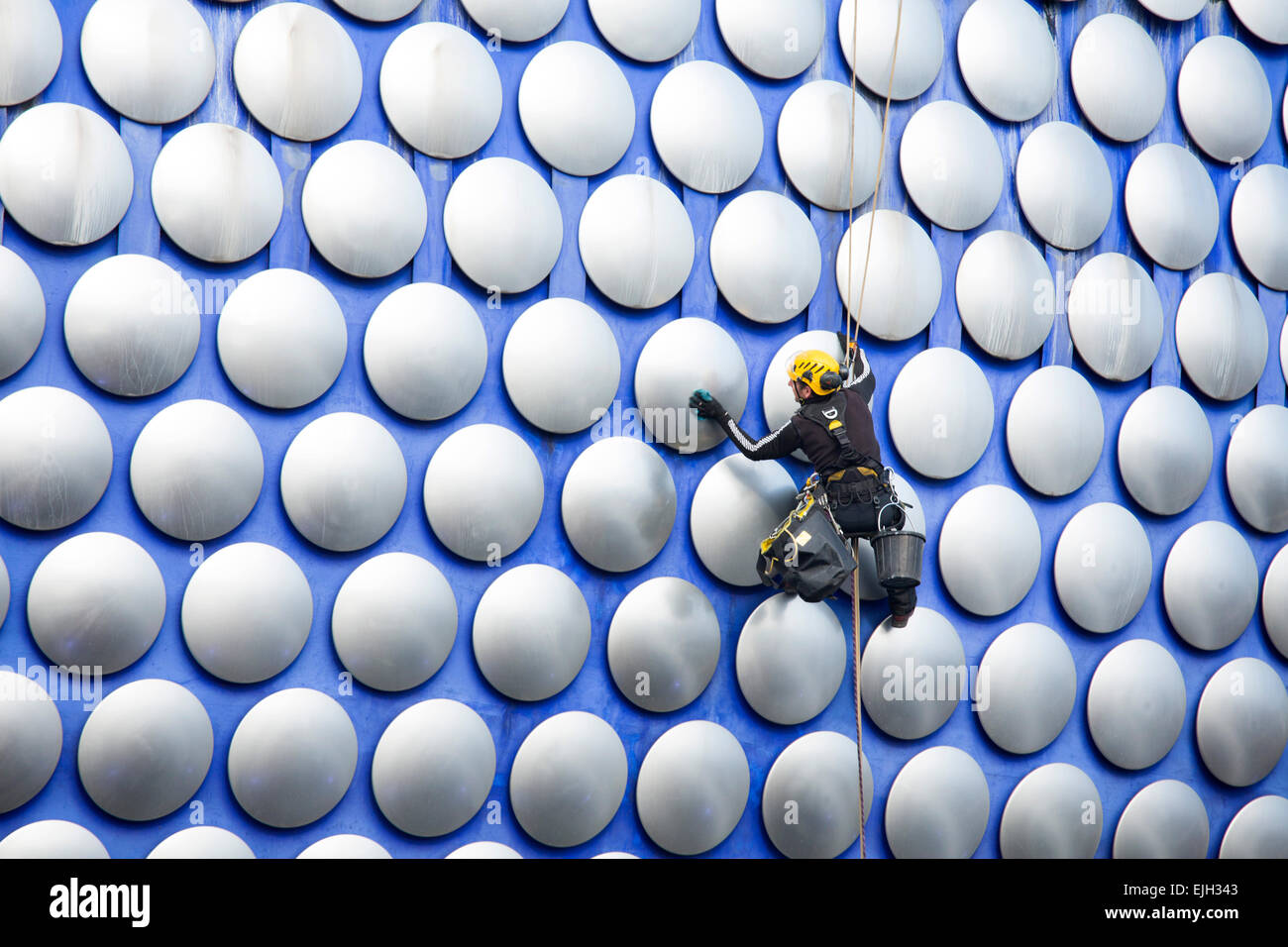 A workman cleaning the decorative discs on the exterior of the Selfridges building in Birmingham Stock Photo