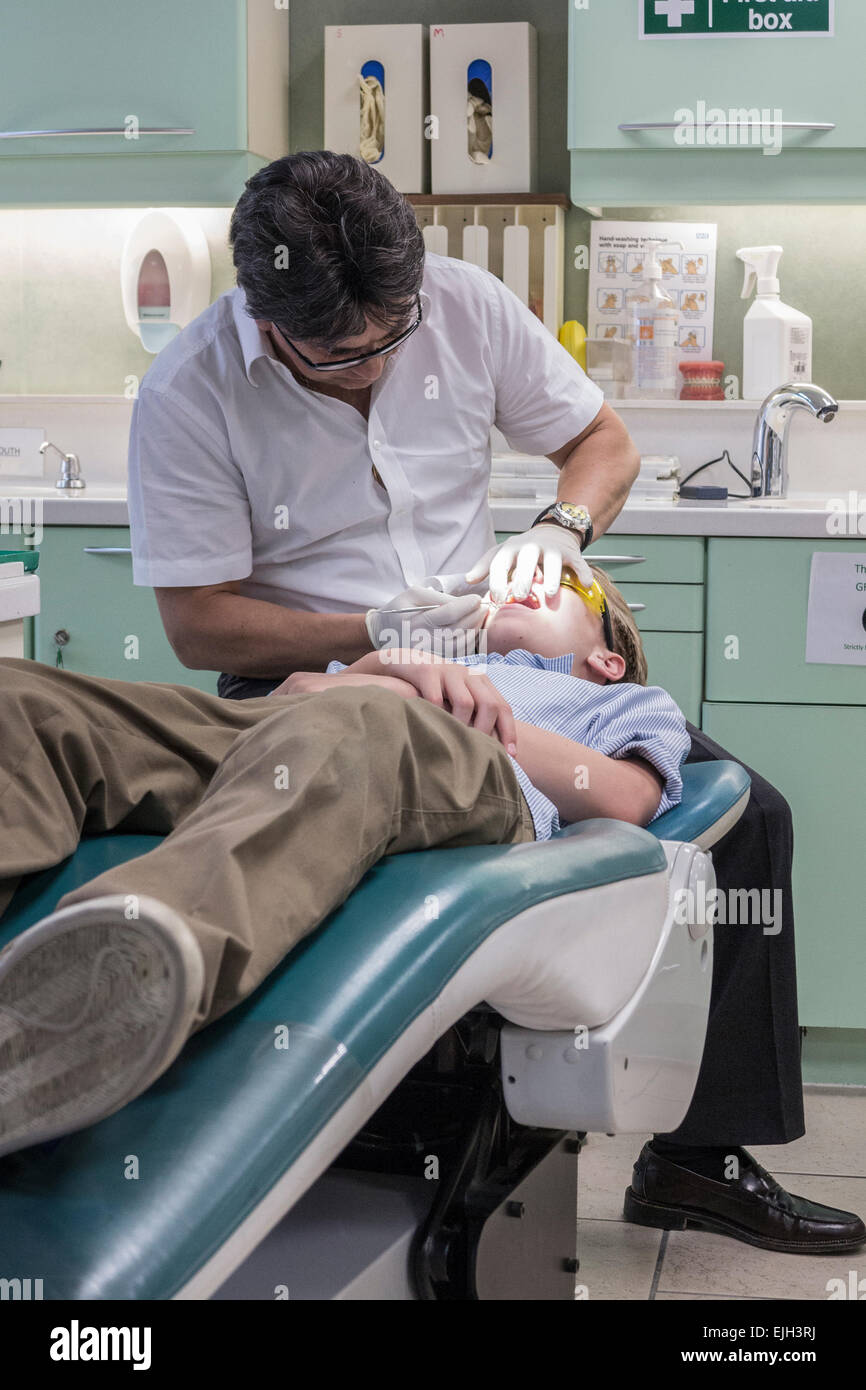 A dentist works on a boys teeth in his dental practice Stock Photo