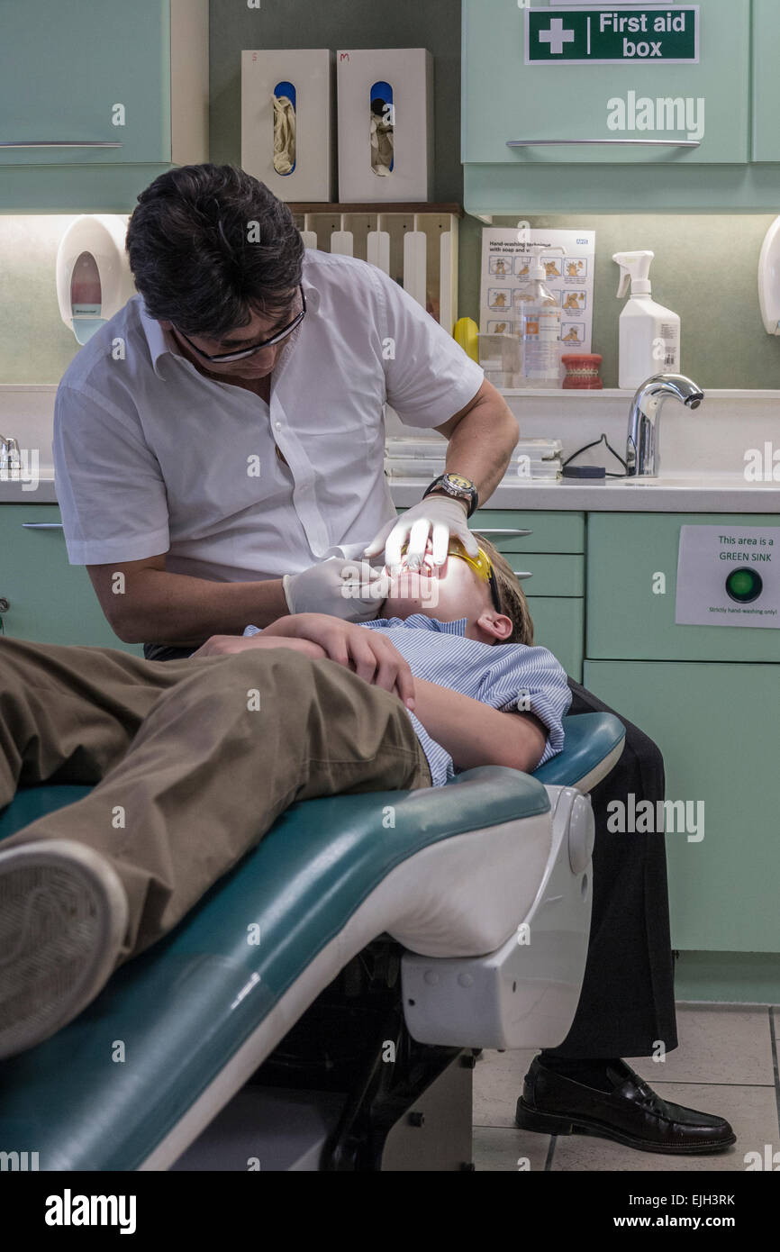 A dentist works on a boys teeth in his dental practice Stock Photo