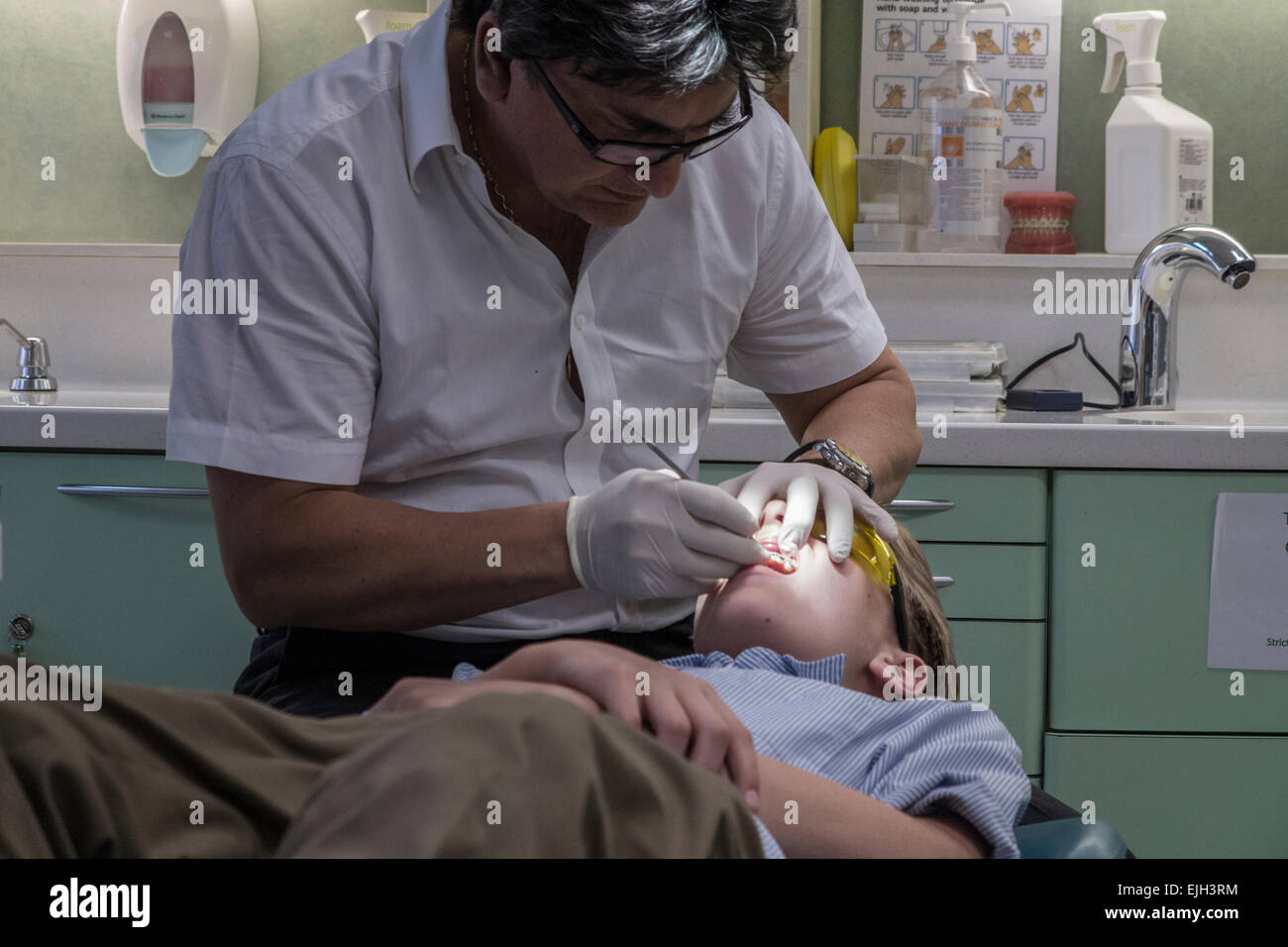 A dentist works on a boys teeth in his dental practice Stock Photo