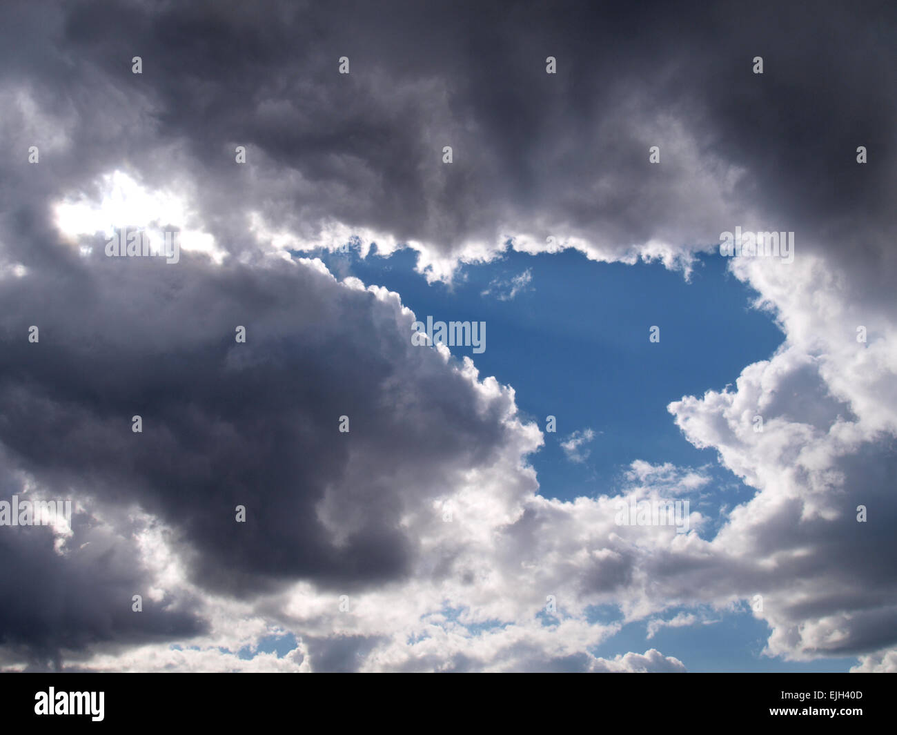 Gap in dark rain clouds in the shape of an arrow on a sunny spring day, Devon, UK Stock Photo