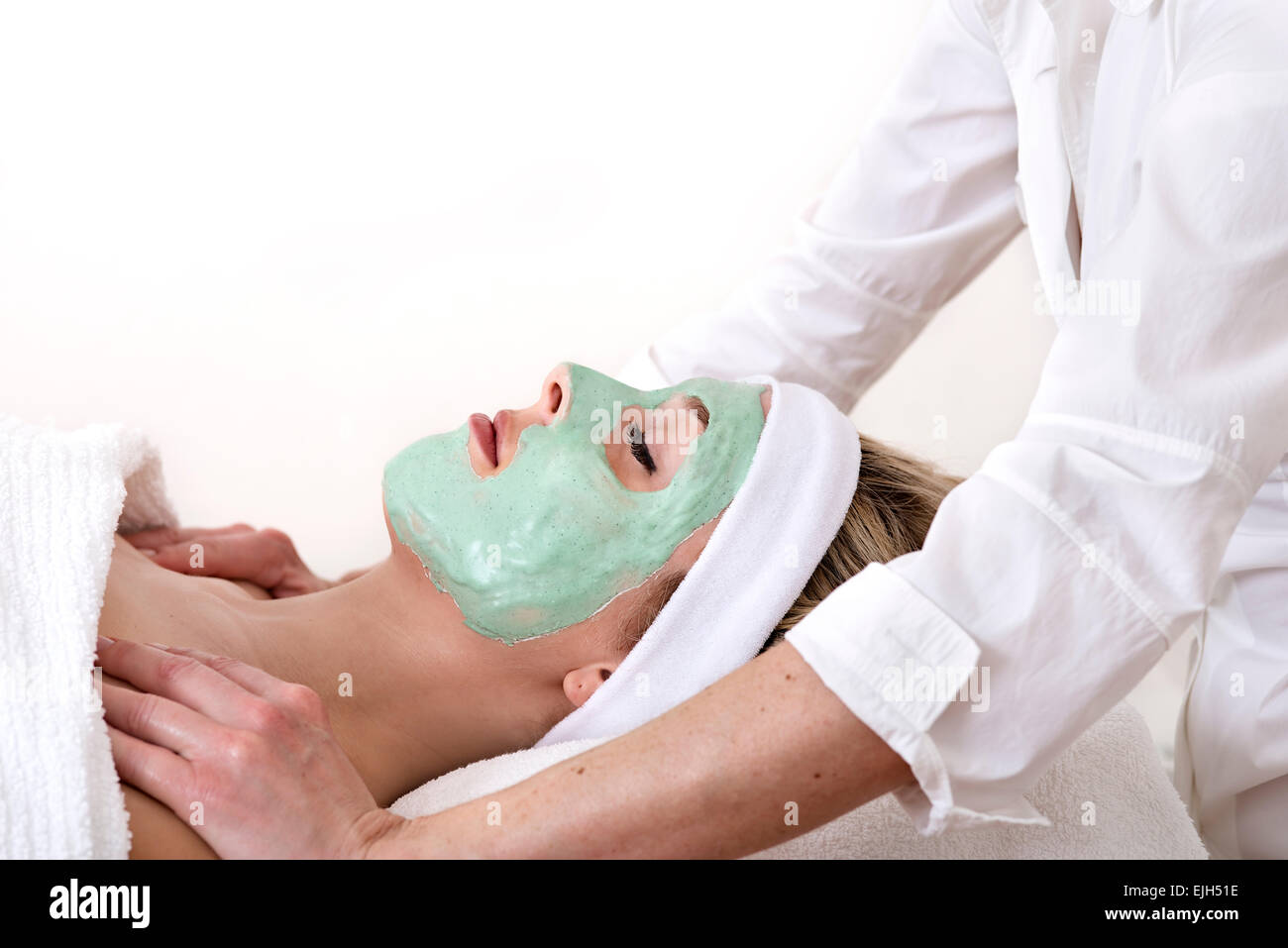 Beautiful woman enjoys a shoulder massage by a masseuse, laid down and with  closed eyes during a green mud thalasso facial beaut Stock Photo - Alamy