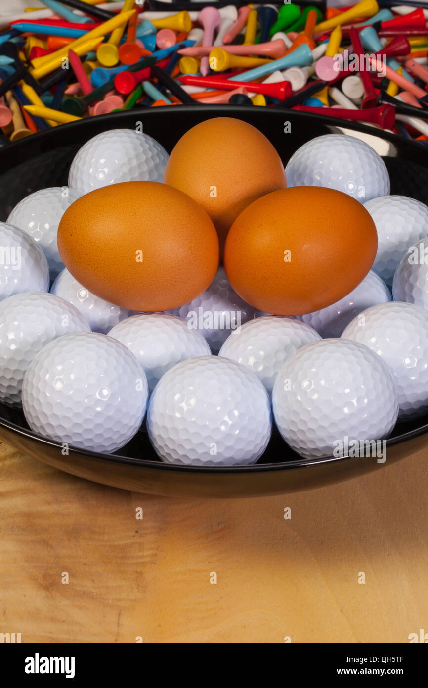 Golf balls and eggs in a black bowl Stock Photo Alamy