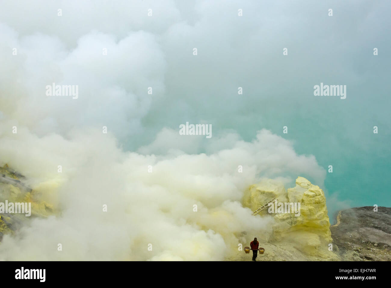 Miners carrying sulfur amid sulfur gas at Ijen crater, East Java, Indonesia Stock Photo