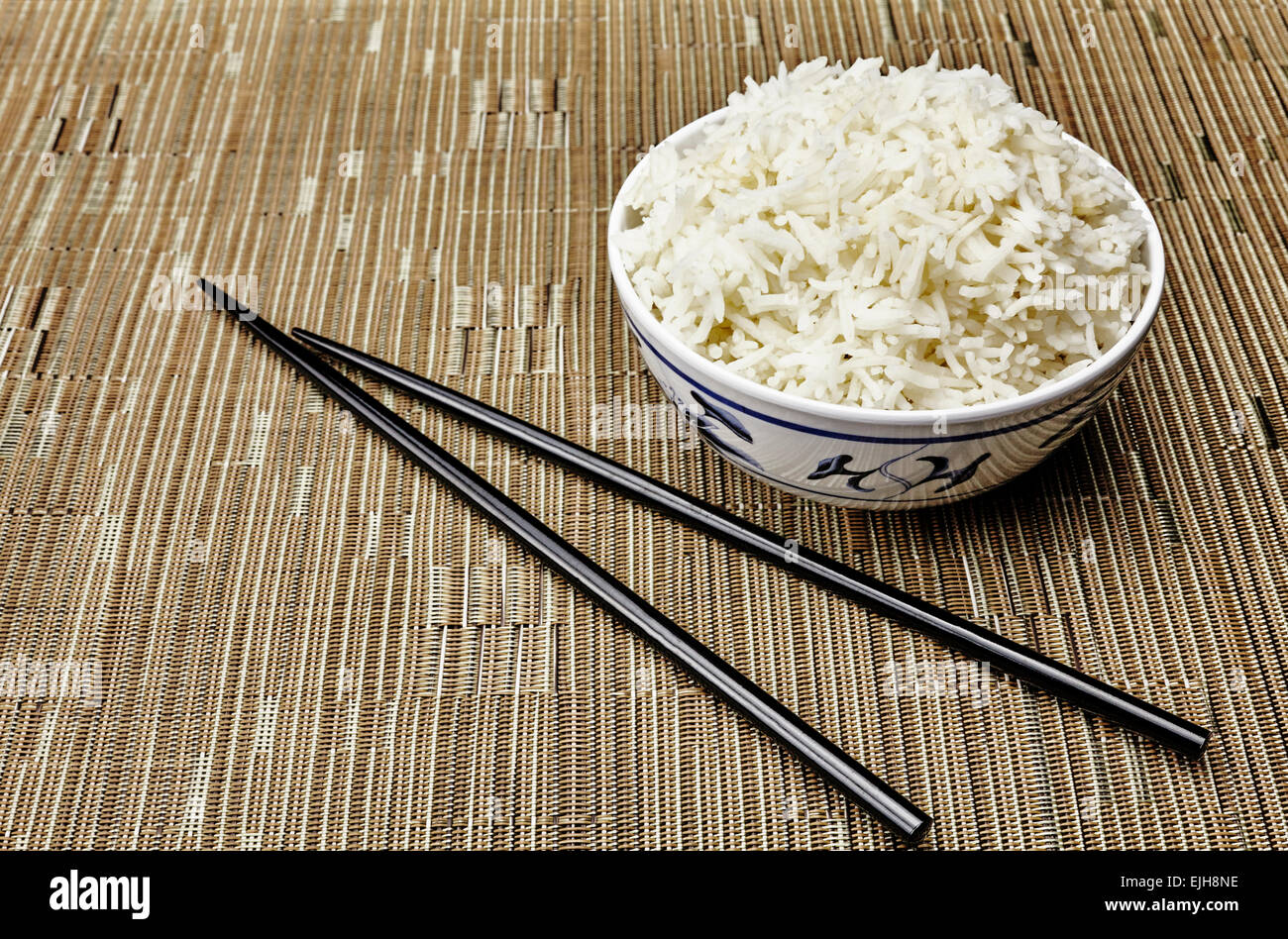 Natural Organic Cooked Jasmine Rice in Oriental Bowl and Chopsticks on tropical style place setting Stock Photo