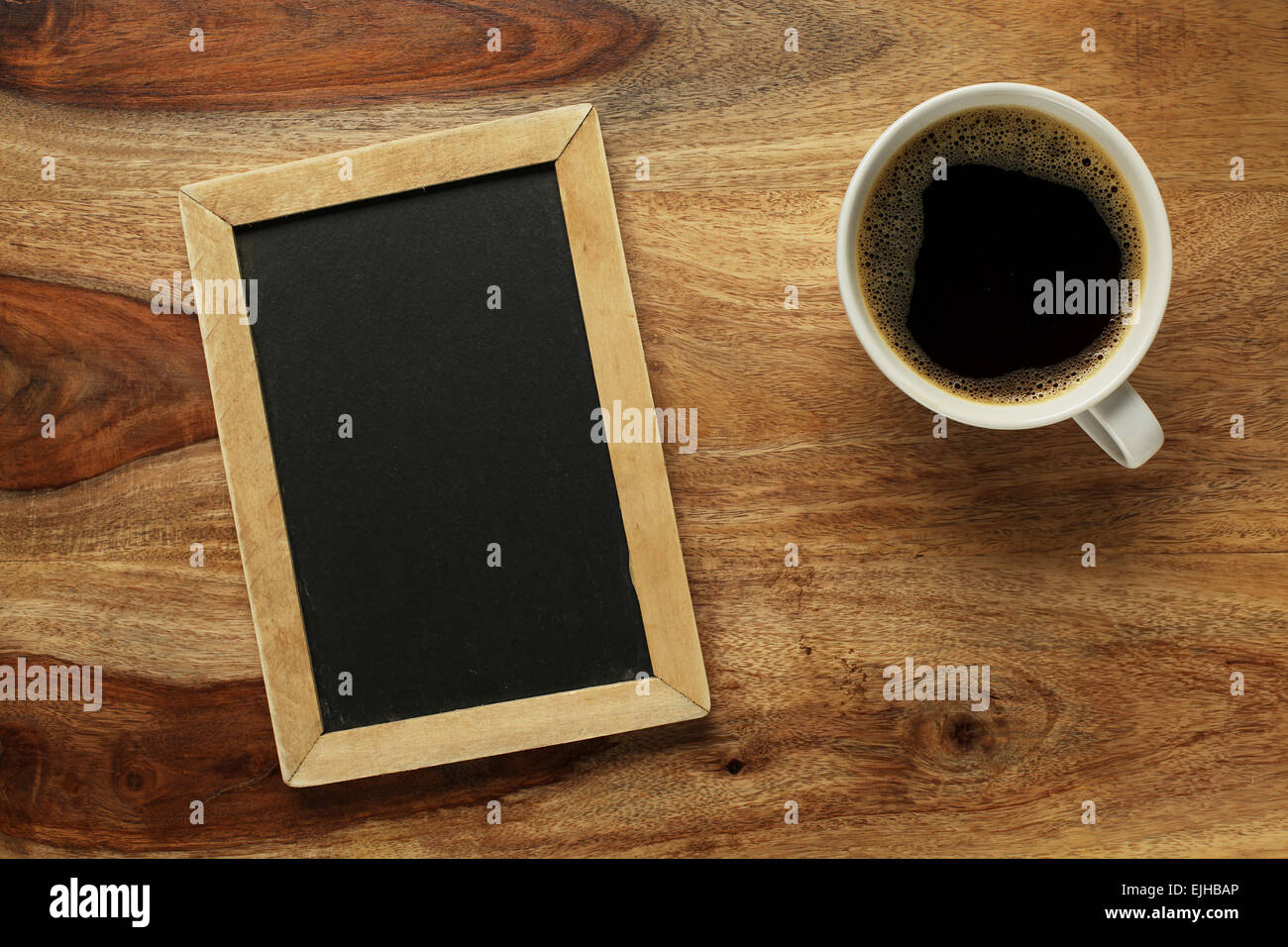 Cup of coffee on desk with blank chalkboard Stock Photo