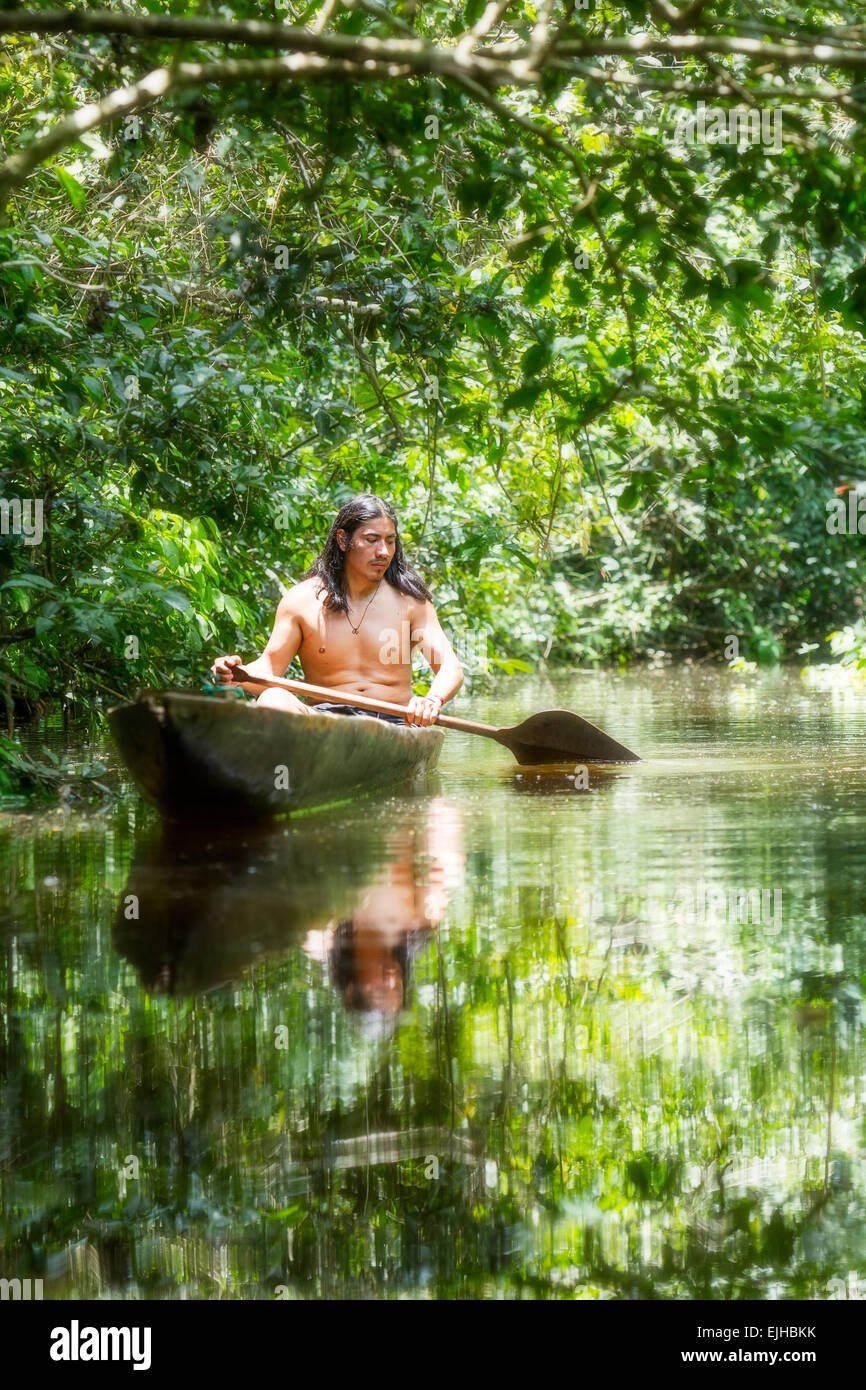 Indigenous Adult Man On Typical Wood Canoe Chopped From A Single Tree Navigating Murky Waters Of Ecuadorian Amazon Primary Jungle Stock Photo