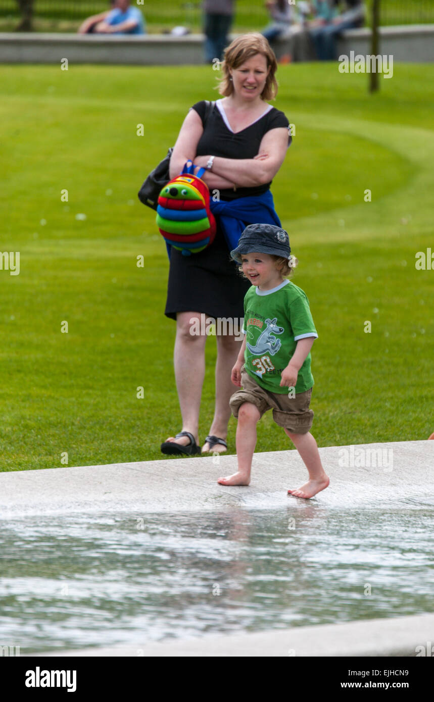 Woman watches child at Princess of Wales Memorial Fountain, Hyde Park, London, England Stock Photo