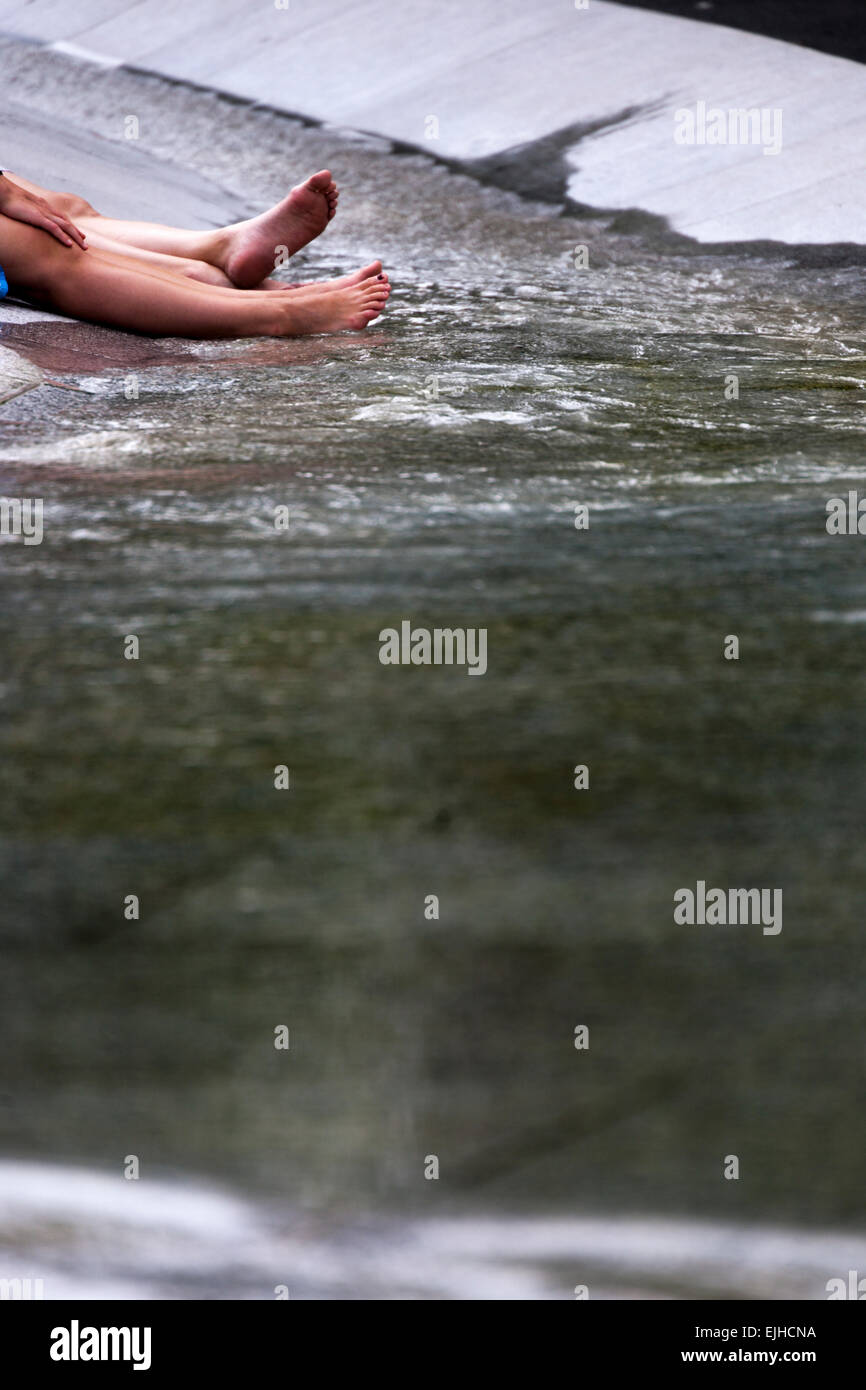 Two people cooling legs and feet in Princess Diana's Memorial Fountain, Hyde Park, London, England Stock Photo