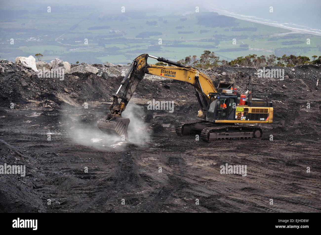 WESTPORT, NEW ZEALAND, MARCH 4, 2015: A digger removes high grade coal from a seam at an open cast coal mine Stock Photo