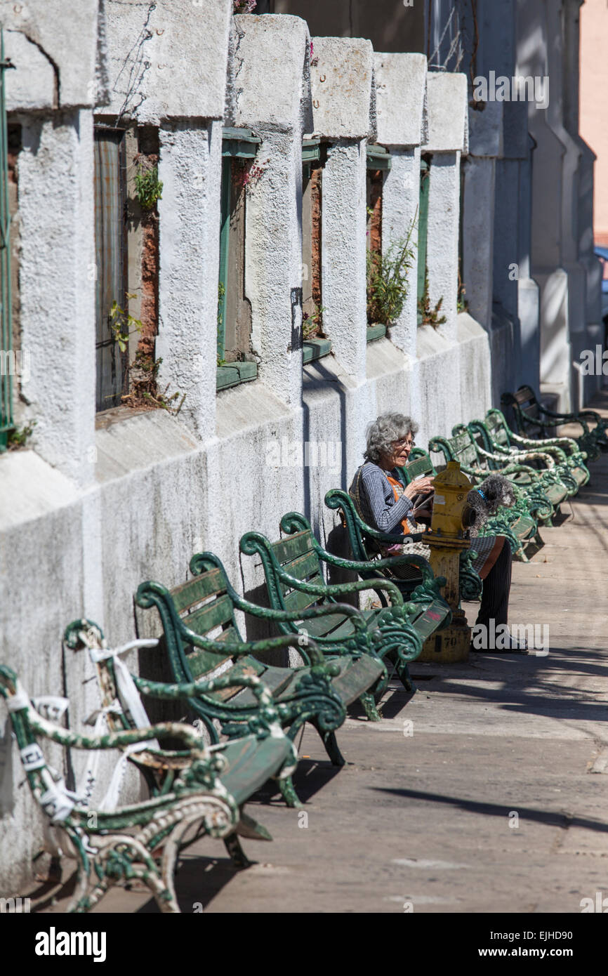 Woman on bench outside church reading newspaper, Valparaiso, Chile Stock Photo