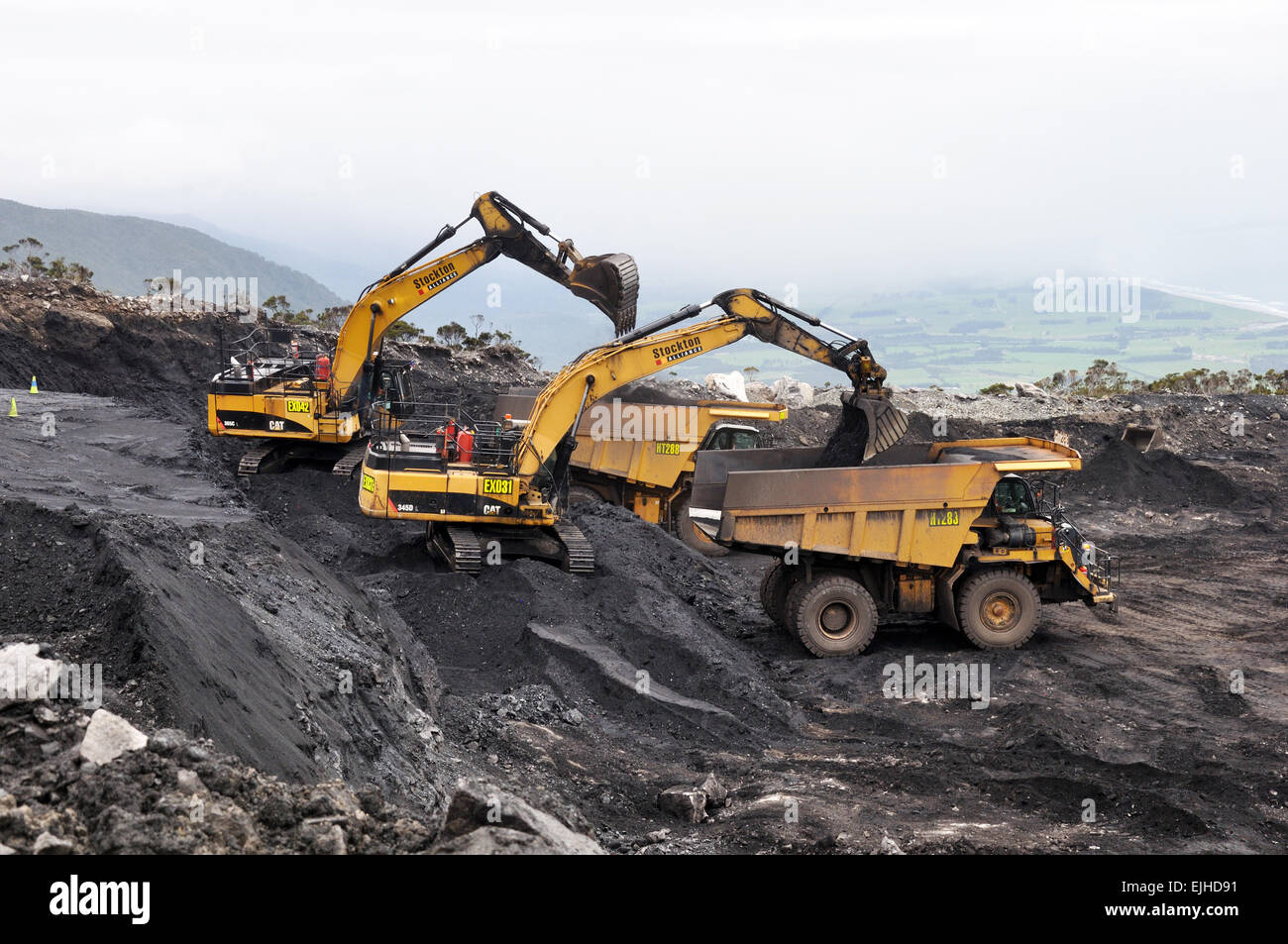 WESTPORT, NEW ZEALAND, MARCH 4, 2015: A pair of diggers remove high grade coal from a seam at an open cast coal mine Stock Photo