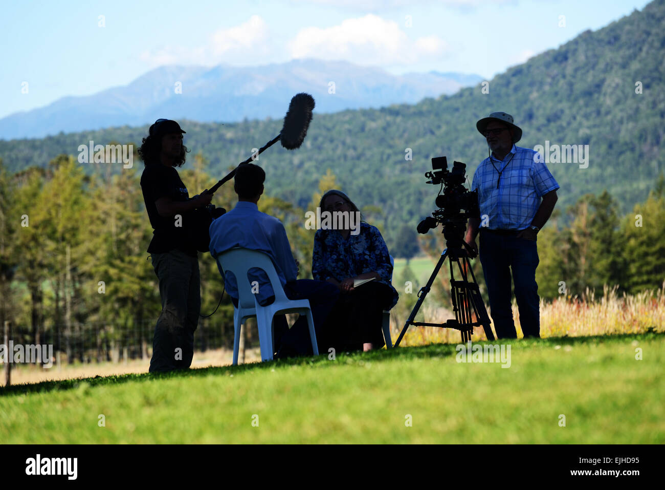 A team of documentary film-makers conduct an interview in the shade Stock Photo