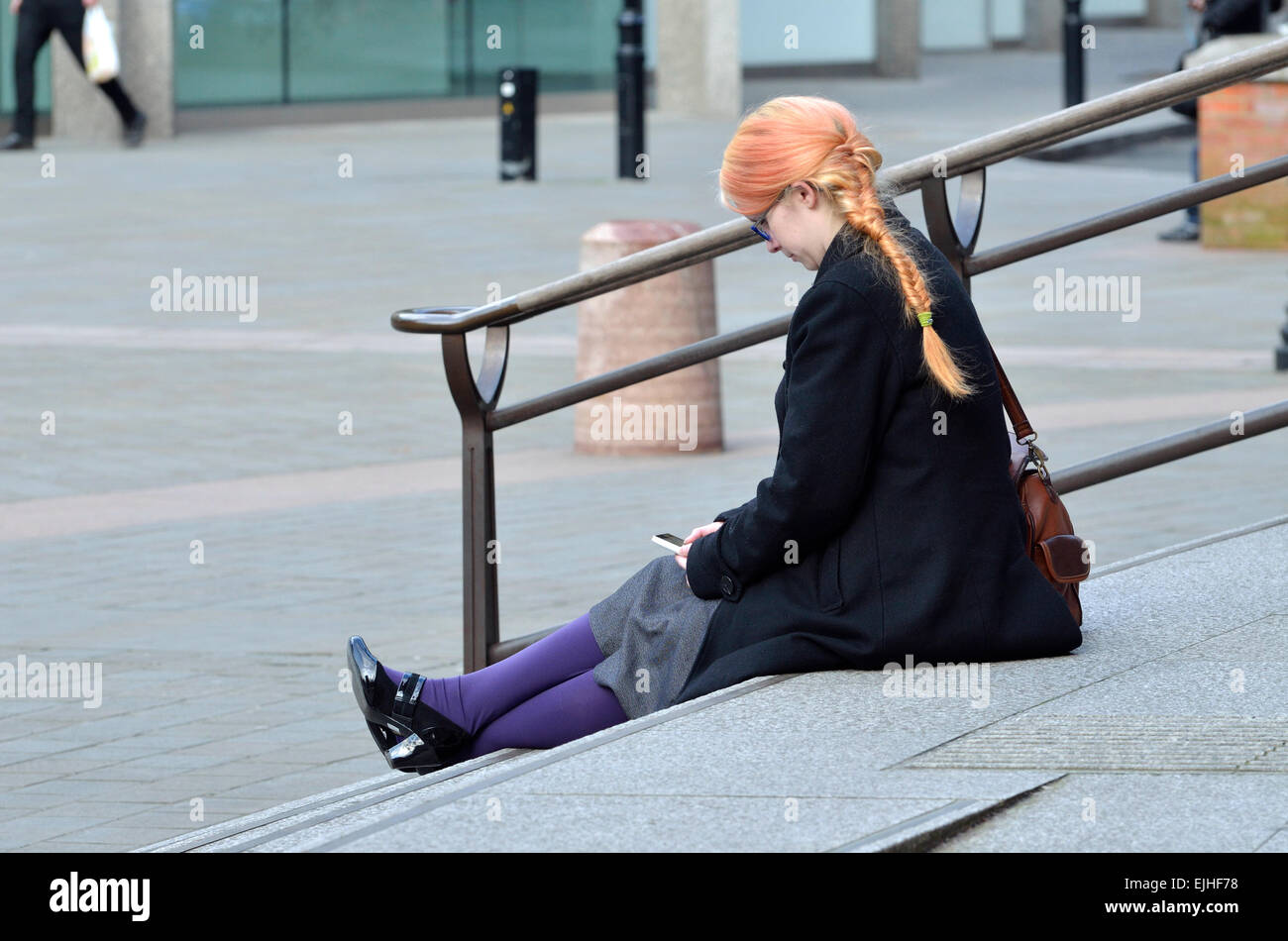 London, England, UK. Young woman with orange hair and purple tights sitting on the steps of Wesminster Cathedral Stock Photo