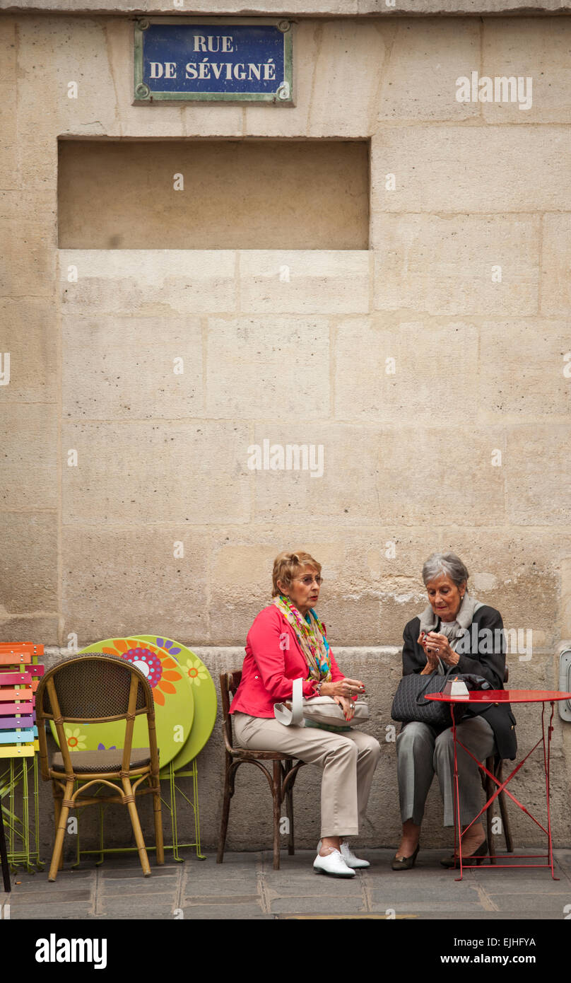 Two women smoking at outdoor cafe in Paris, France Stock Photo