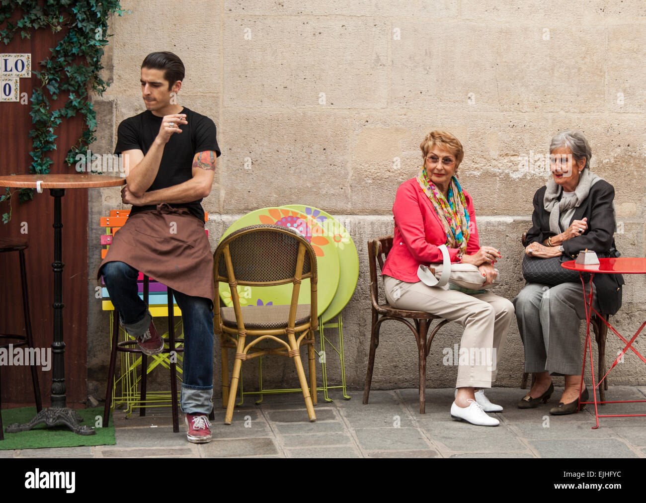 Waiter and two women smoking outside cafe in Paris, France Stock Photo