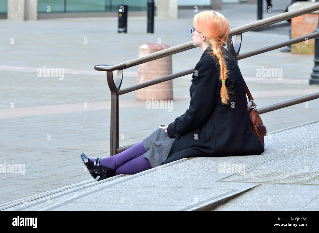 London, England, UK. Young woman with orange hair and purple tights sitting on the steps of Wesminster Cathedral Stock Photo