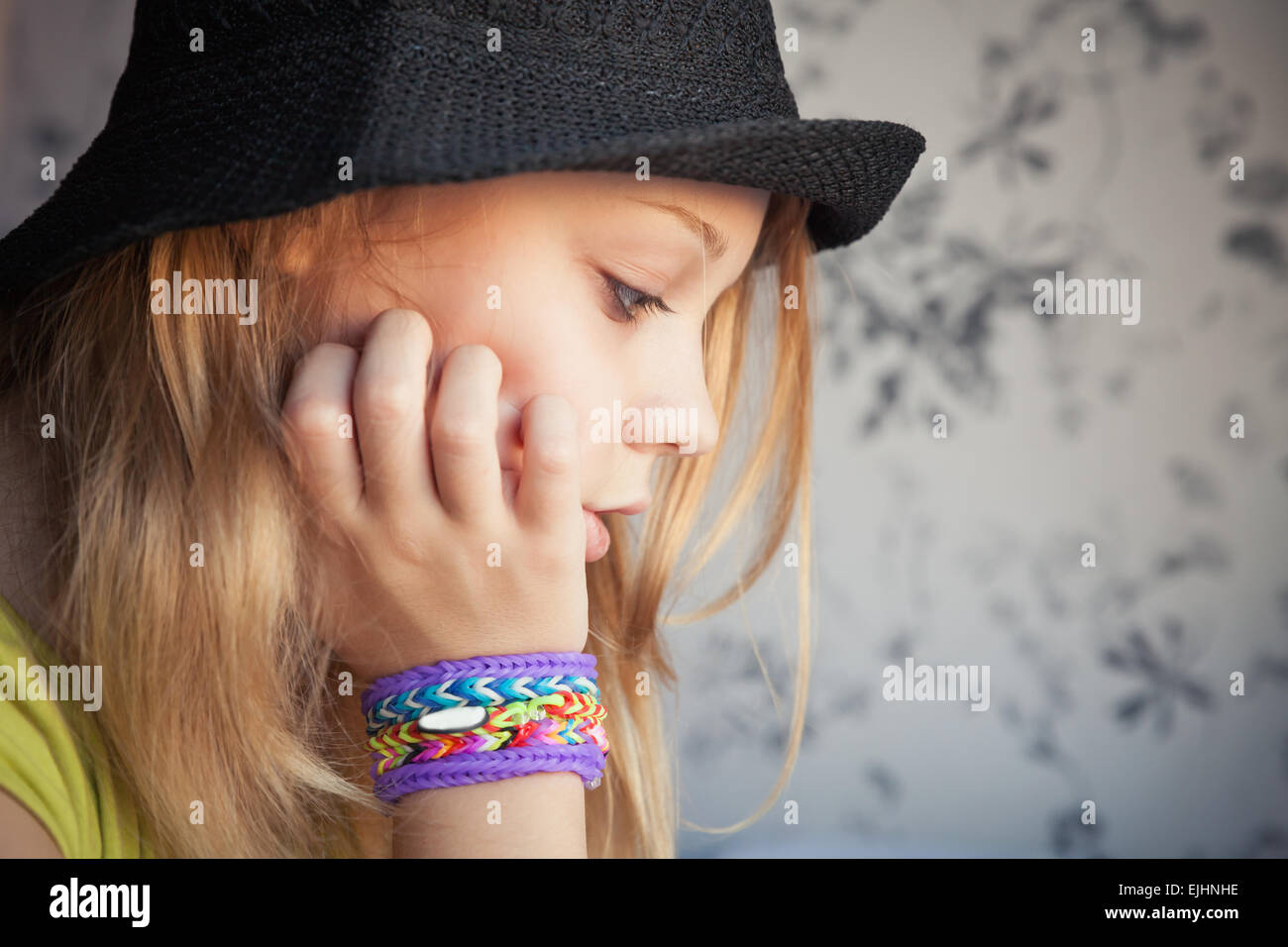 Profile portrait of beautiful blond teenage girl in black hat and rubber loom bracelets, toned photo, instagram style effect Stock Photo