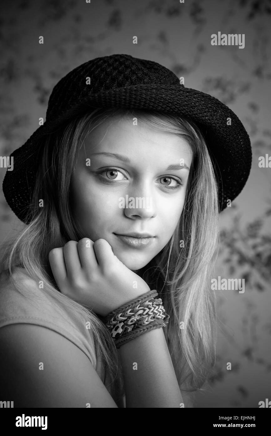 Monochrome portrait of beautiful blond teenage girl in black hat and rubber loom bracelets Stock Photo