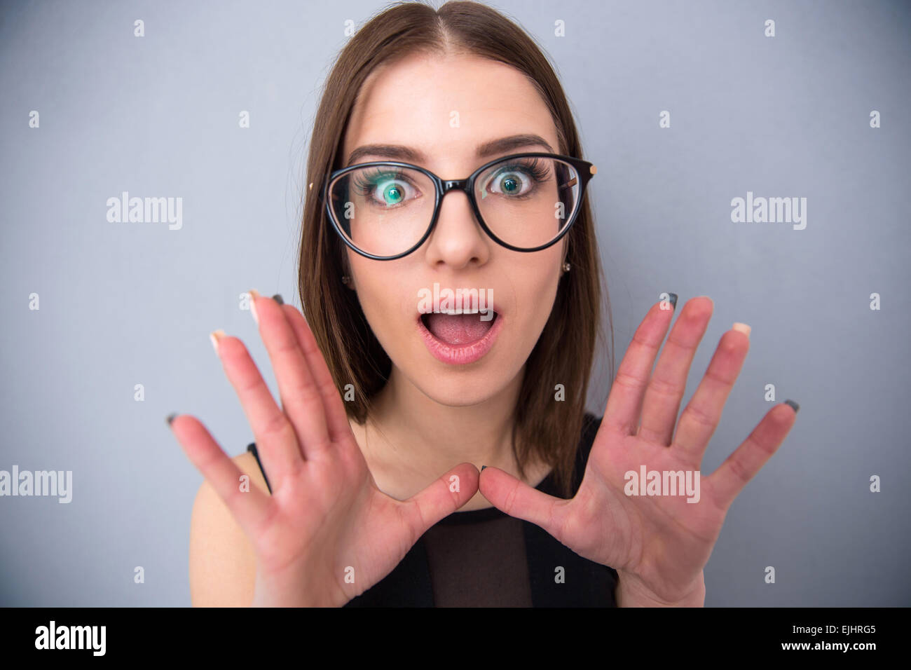 Closeup portrait of a surprised woman looking at the camera. Standing over gray background Stock Photo