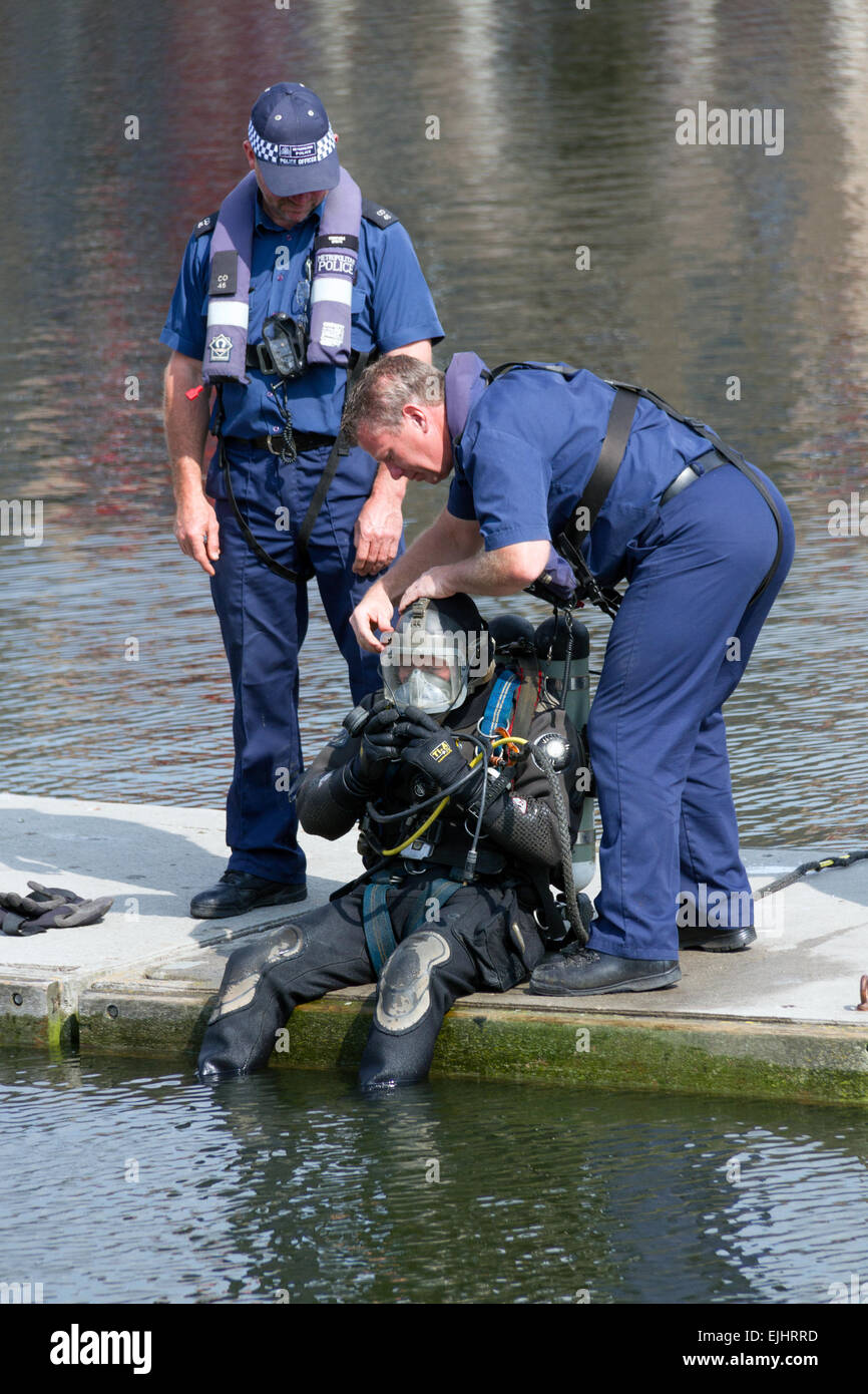 Colleagues from the Metropolitan Police Service Marine Support Unit help a colleague prepare to dive during an exercise. Stock Photo