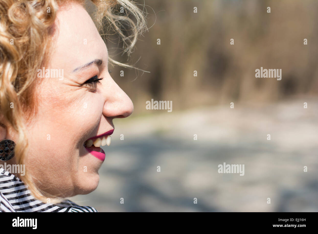 Closeup portrait of a pretty young woman with blond curly hair laughing out loud Stock Photo