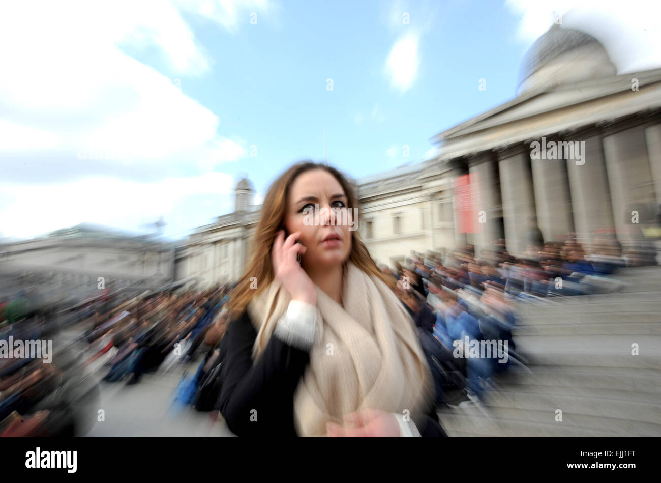 London England UK Young woman on her mobile phone in busy Trafalgar