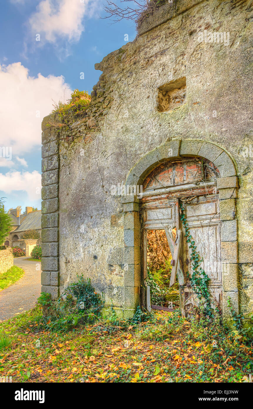 Old medieval abandoned house in a village with broken door and plants groving inside, France, Brittany Stock Photo