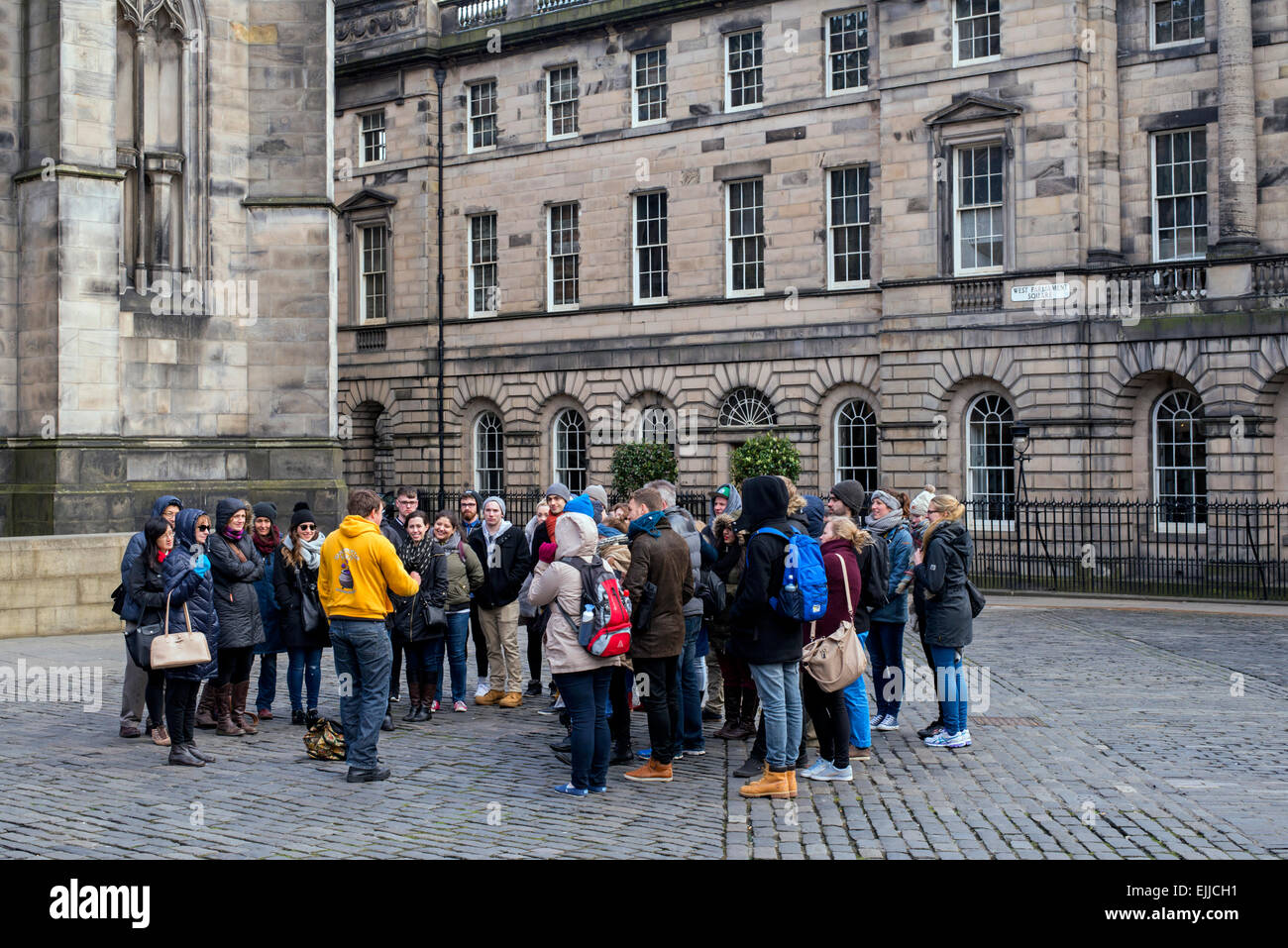 A group of tourists on a guided walking tour visit Parliament Square on the Royal Mile in Edinburgh, Scotland, UK. Stock Photo
