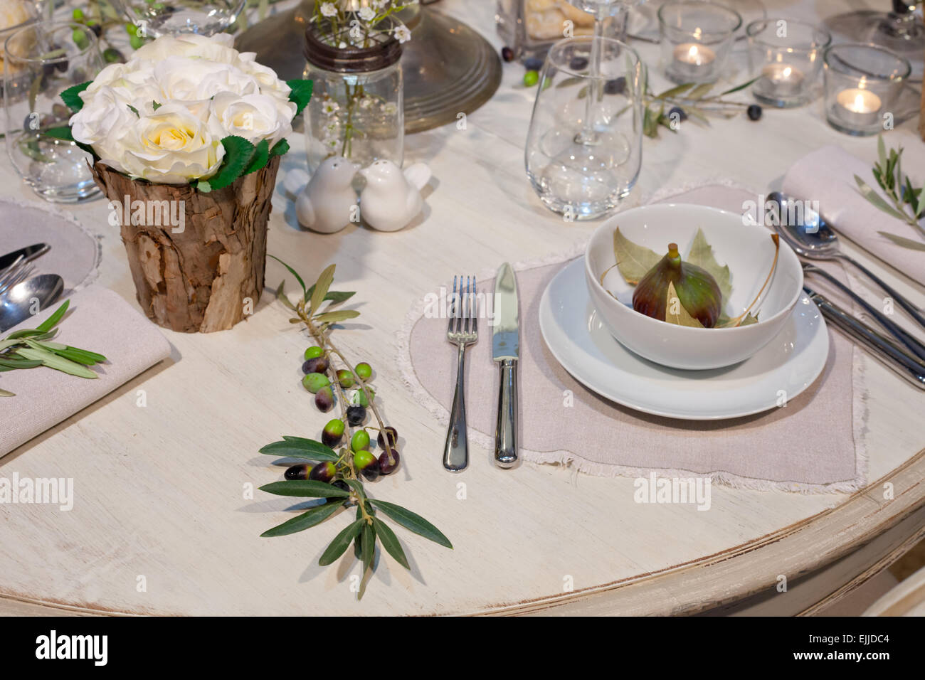 Decoration of wedding table with wooden trunk vases, figs, and olives