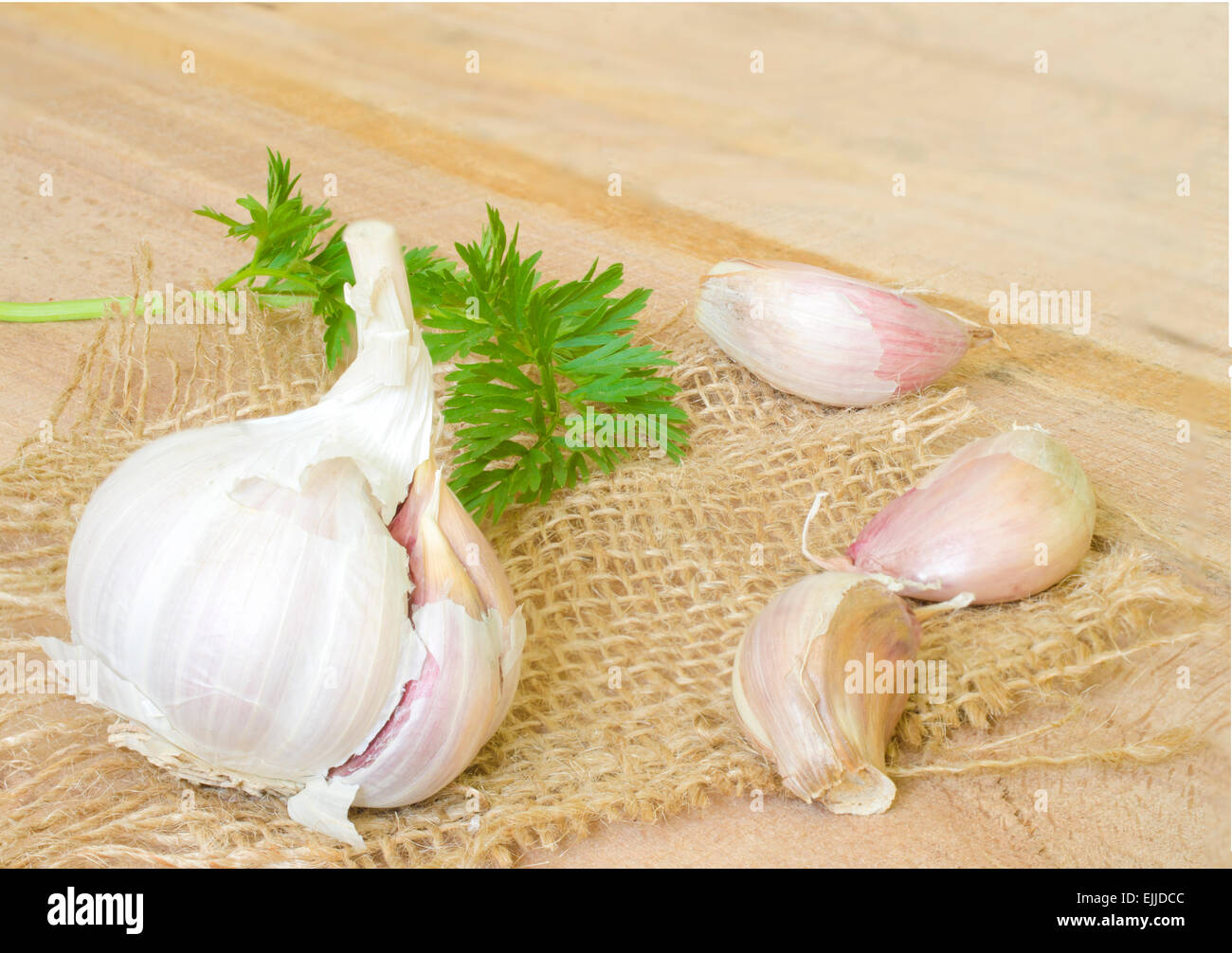 Garlic and parsley leaves on canvas isolated on wood Stock Photo