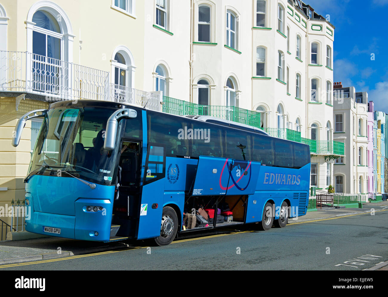 Tourist coach parked outside hotel, with luggage compartment open, Stock Photo