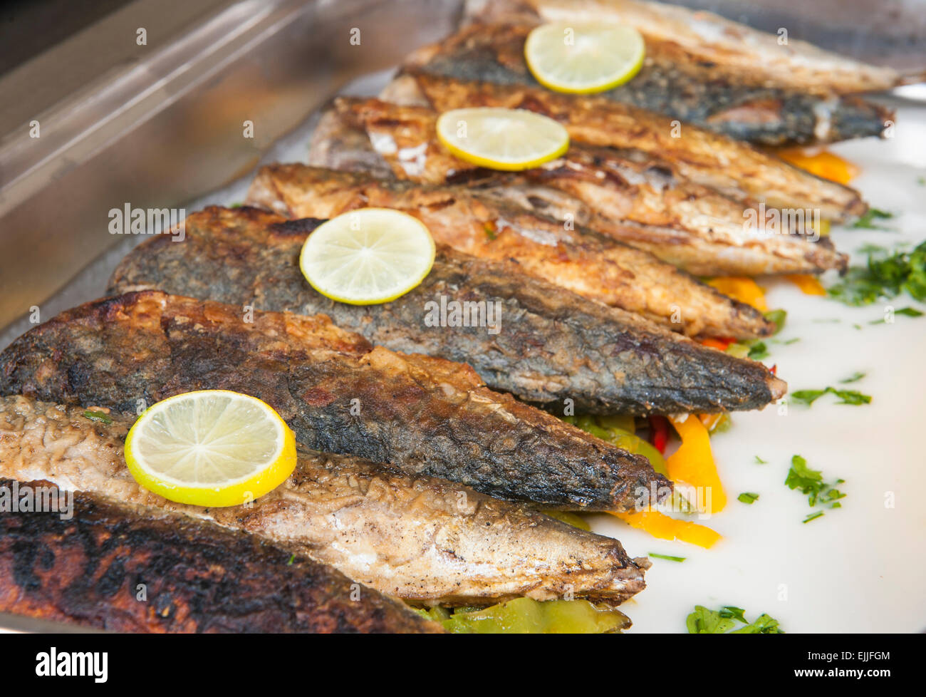 Row of grilled mackerel fish with lemon on display at a hotel