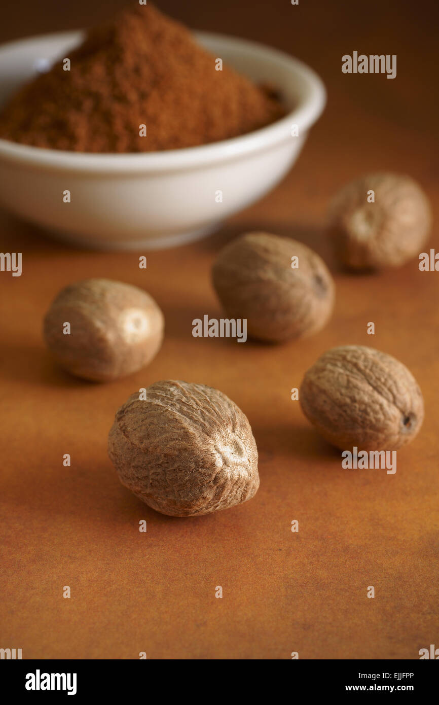 Whole and ground nutmeg a fragrant spice from the fruit of Myristica fragrans indigenous to the Banda Islands of Indonesia Stock Photo