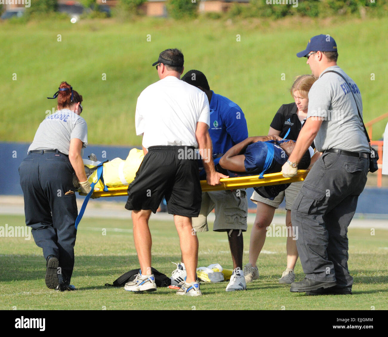 Medical personnel transport injured football player off the field on a backboard Stock Photo
