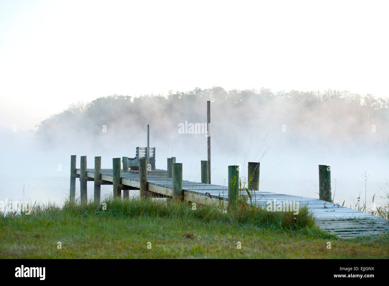 A pier engulfed with fog that is rolling in early morning Stock Photo