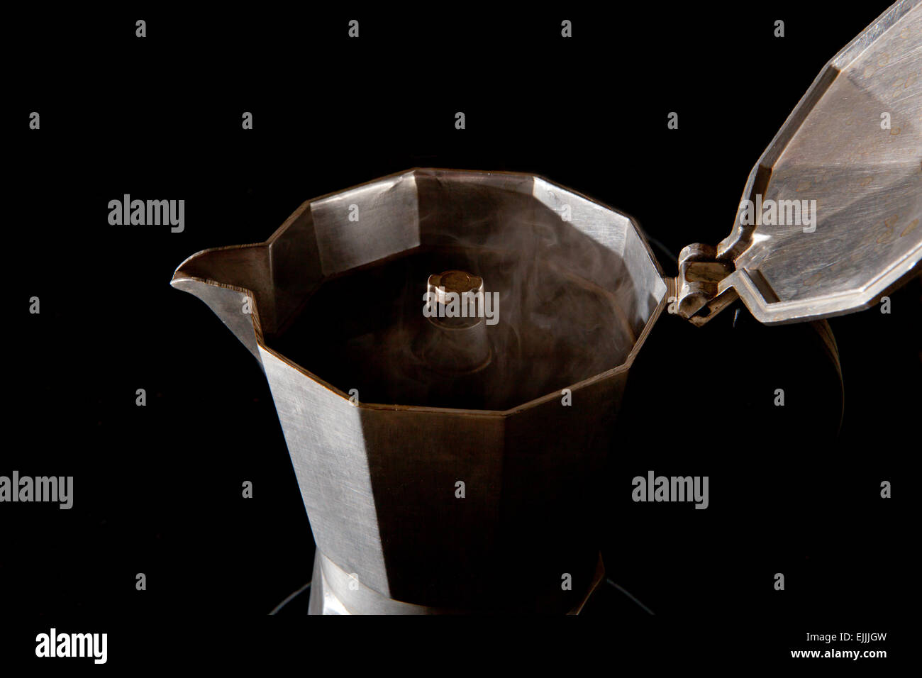 Steaming espresso coffee maker interior isolated over black background