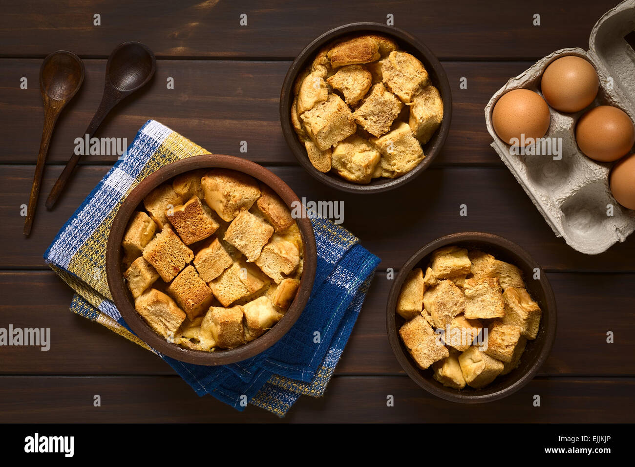 Overhead shot of three rustic bowls of bread pudding made of diced stale bread, milk, egg, cinnamon, sugar and butter Stock Photo