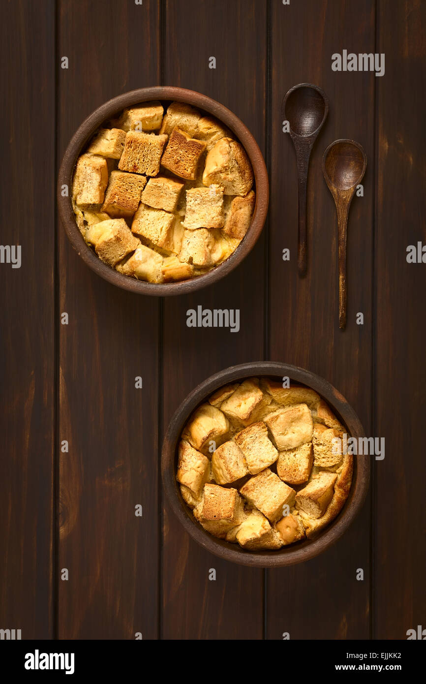 Overhead shot of two rustic bowls of bread pudding made of diced stale bread, milk, egg, cinnamon, sugar and butter Stock Photo